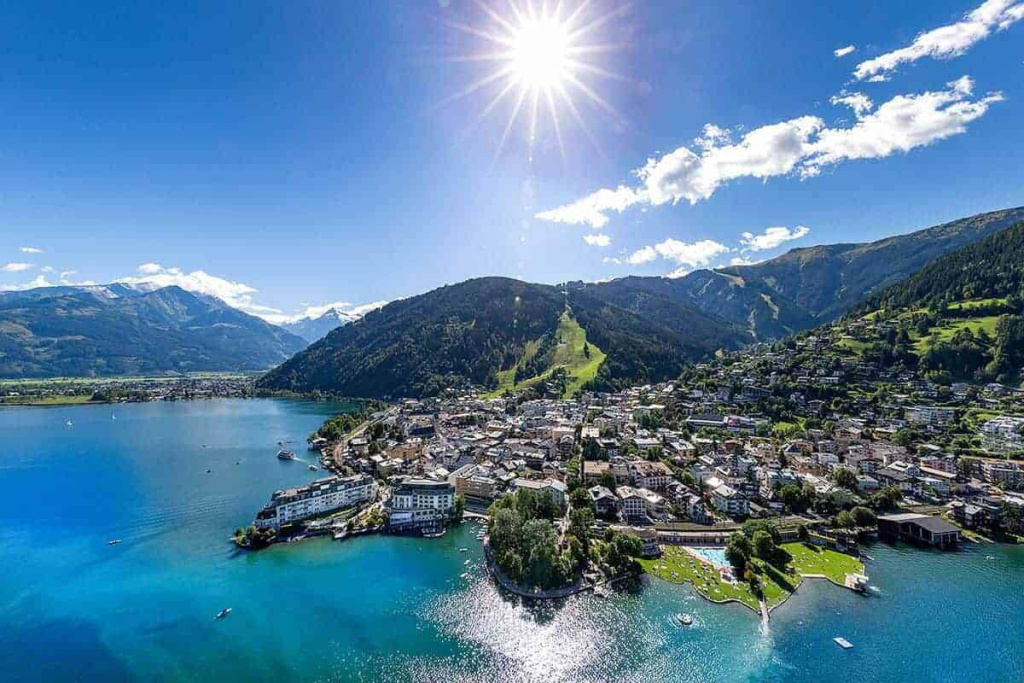 Sommerliche Uferstadt an einem klaren Bergsee mit umliegenden grünen Bergen